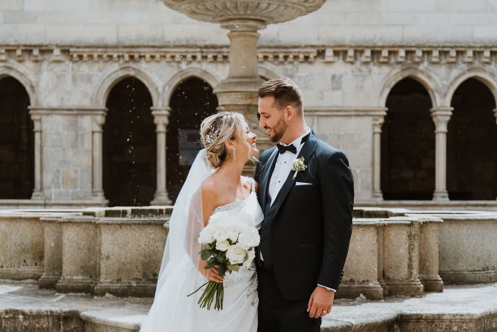 Casal sorrindo em frente a uma fonte